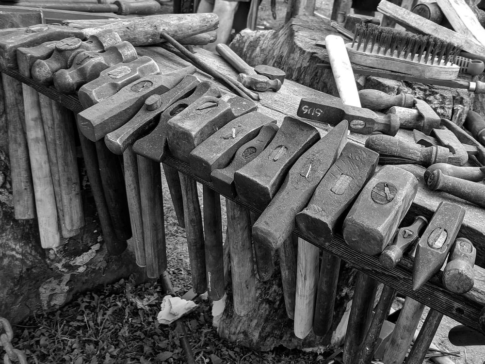Blacksmith's hammers lined up on a forge workbench